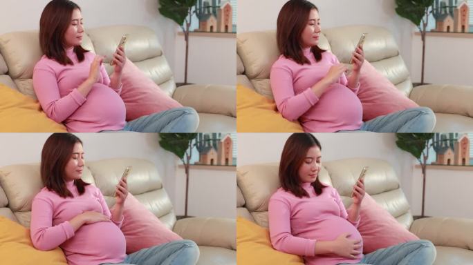 亚洲孕妇坐在沙发上，在家用手机享受网上购物