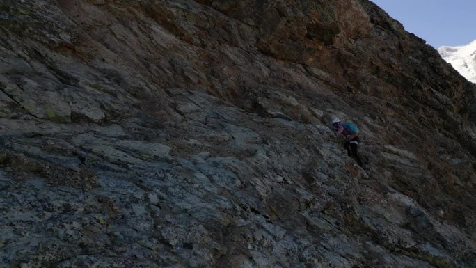 一名妇女在阿尔卑斯山的Ferrata大道上攀登，在冰川之上