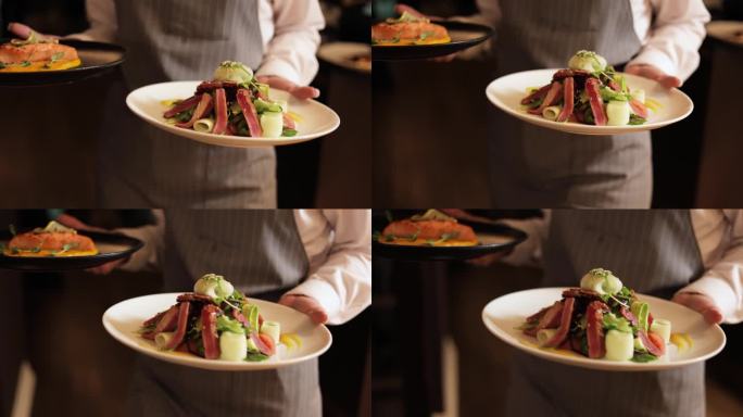 专业的女服务员，系着优雅的围裙，双手端着盛有精美菜肴的盘子为客人服务。优质的服务和精美的烹饪杰作。