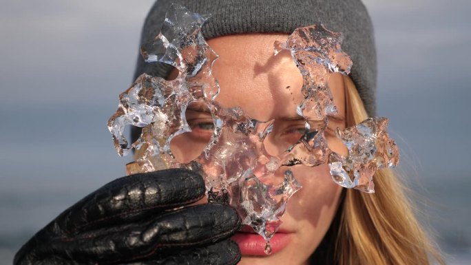 在冰岛钻石沙滩上，金发美女透过浮冰向外张望