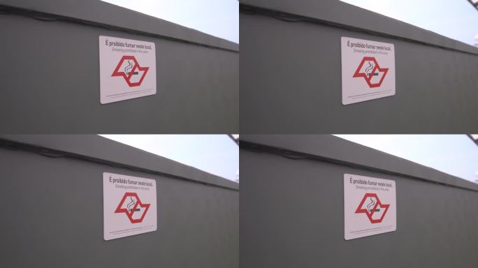 灰色的墙上挂着双语禁烟标志，标明吸烟限制