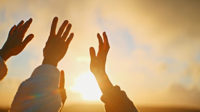 慢镜头:年轻的女人在日出时朝着金色的阳光举起双手