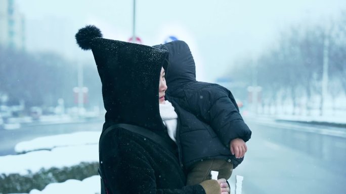 下雪天年轻妈妈带着孩子在等车