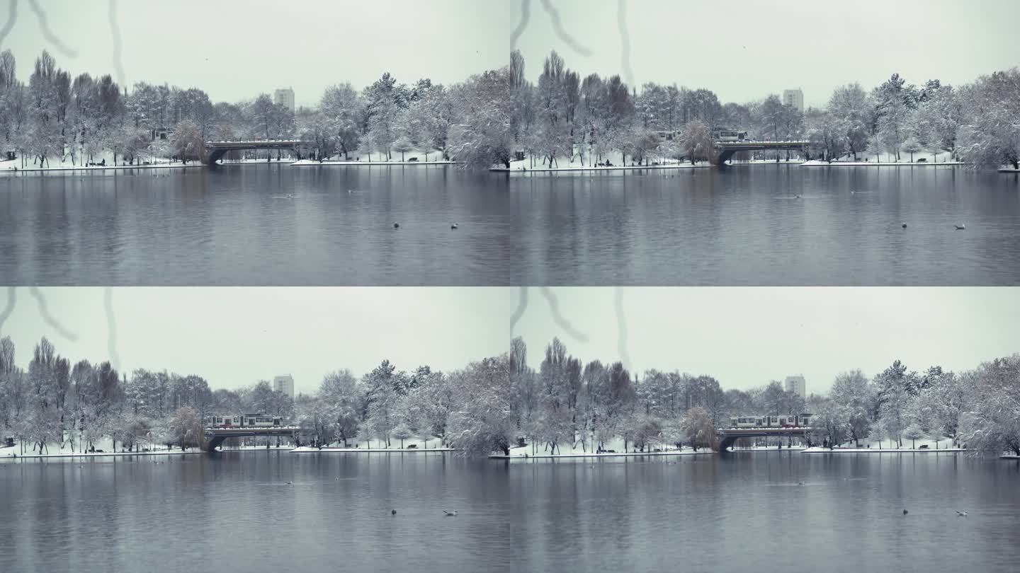 广角静态拍摄的城市景观，在一个公园的湖泊，建筑和桥梁上的交通在冬天下雪