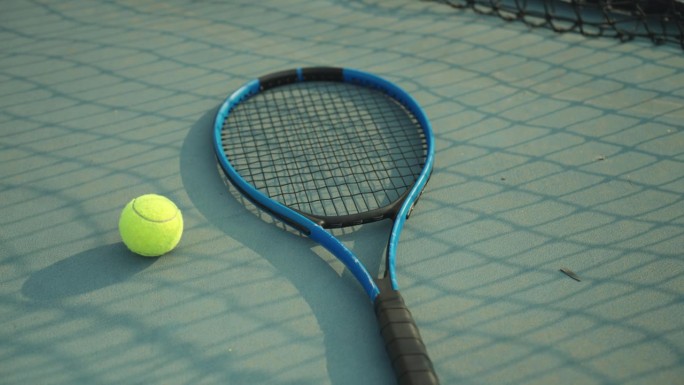 绿色的网球场地板上，一个绿色的网球和蓝色的球拍。