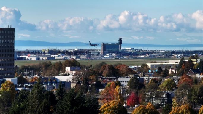 抵达的飞机降落在温哥华国际机场，可以看到控制塔和YVR地铁站。广角镜头