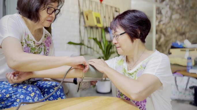 70多岁的亚洲老太太们从小就是好朋友，她们穿着相似的姐妹装，互相帮助测量血压。