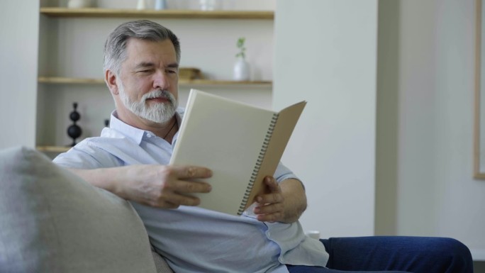 老快乐和放松的人坐在家里看书的肖像特写