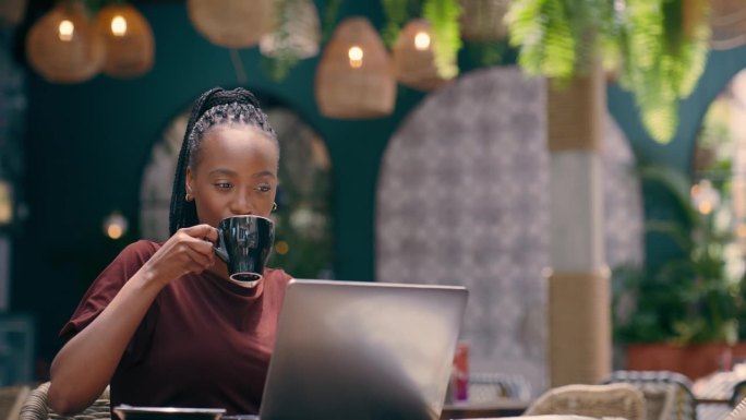 手提电脑，喝咖啡，和一个快乐的黑人女人在咖啡馆里远程工作，打字或者写博客。电脑，餐厅和自由编辑写文章
