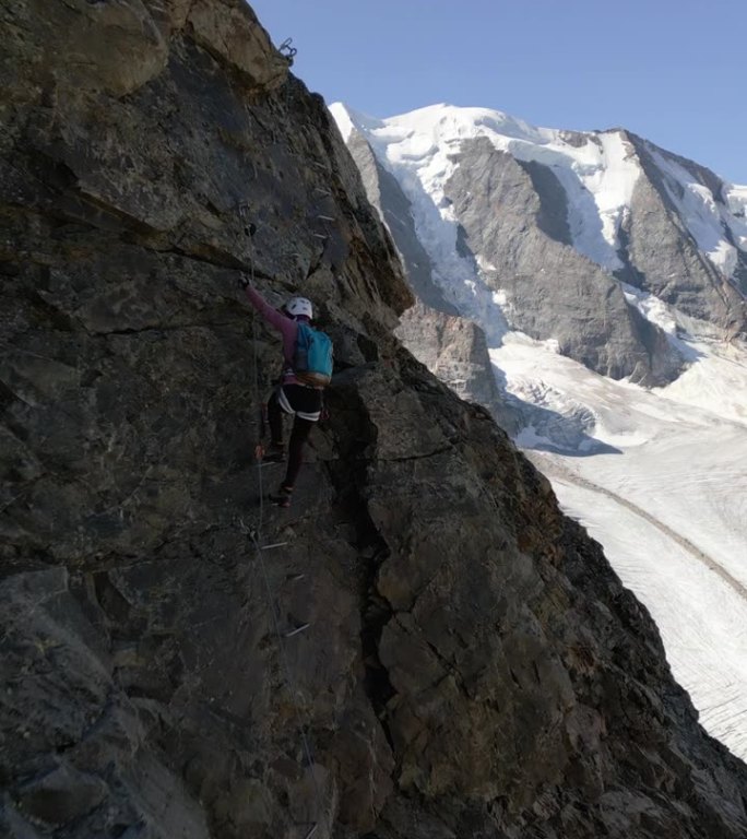 鸟瞰图，一名妇女在阿尔卑斯山的Ferrata大道上攀爬，在冰川之上