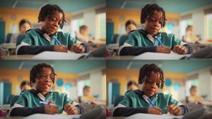 一个可爱的黑人小男孩的肖像，带着可爱的微笑坐在课桌后面。年轻的学生专注于一堂课，和其他孩子一起听老师