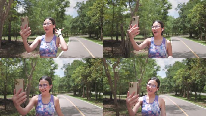 运动女性网红一边在公园慢跑锻炼，一边用智能手机录制视频博客直播，上传到社交媒体