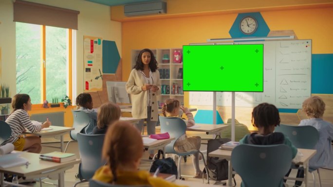 小学生在课堂上的信息时间:女教师在现代彩色教室里用模拟绿屏电视教育聪明多样的孩子