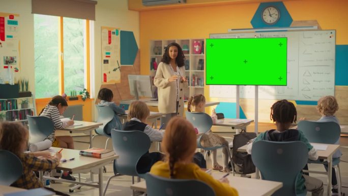 女教师在模拟电视绿幕模板上展示信息。好奇的小学生有兴趣学习新事物，获得知识和技能