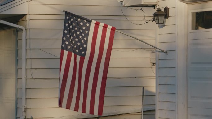 一面美国国旗在农舍的门廊上飘扬