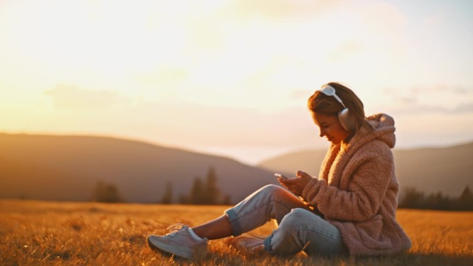 年轻女子戴着耳机在山野听音乐