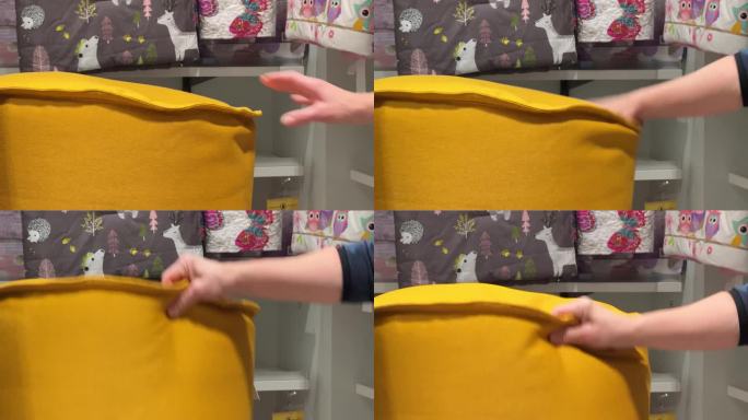 女性的手在测试黄色的撅嘴。一位妇女在家纺部检查一把黄色的豆袋椅。手的特写，模糊的背景。