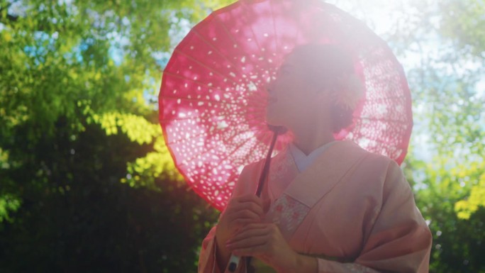 穿着日本和服的美女手持红色雨伞在森林风景中呼吸