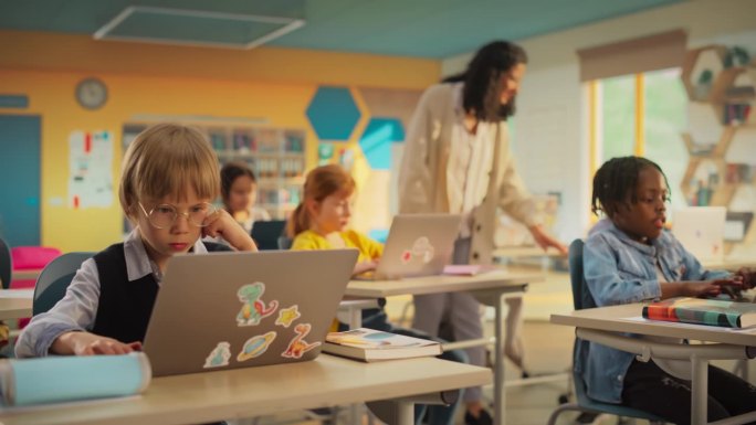 多民族儿童在小学学习STEM和信息技术学科时使用笔记本电脑的班级。快乐的女老师教育聪明的男孩和女孩
