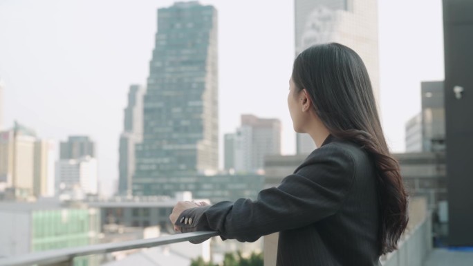 亚洲女人在屋顶上看城市风景