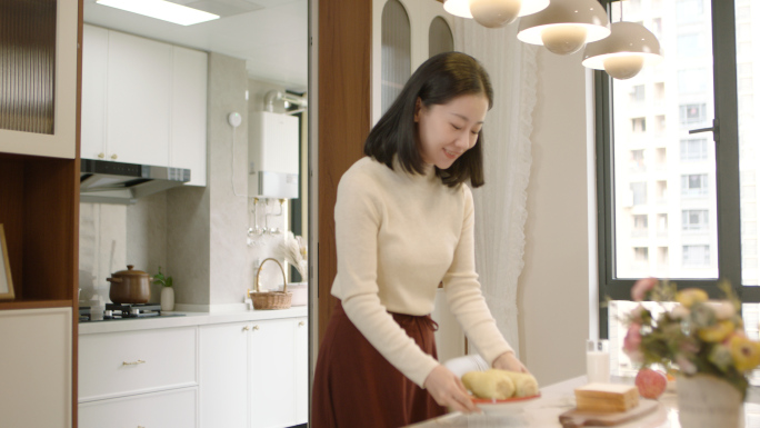 女人从厨房端早餐到餐桌