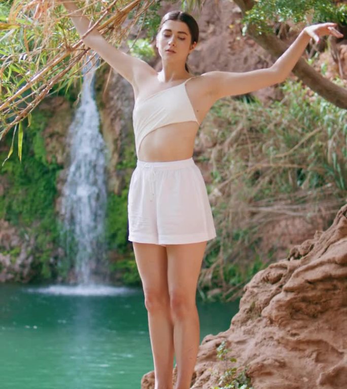 赤脚女人伸展身体，绿松石湖自然垂直。瑜伽女孩暖身