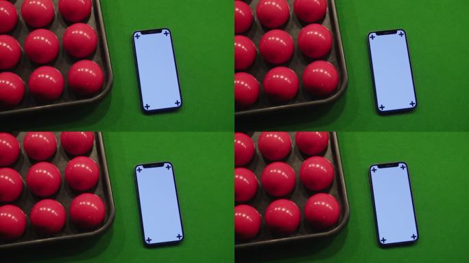 色度键手机在绿色台球桌的红色球之间。台球比赛。绿屏智能手机