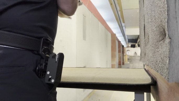 男子用现代手枪和枪套训练动态射击，在室内射击场快速装填和射击