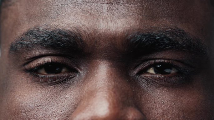 黑人男子脸的肖像与大眼睛看着相机近距离。具有民族特征的非裔美国成年人的严重视力。非洲人的现代观观与思