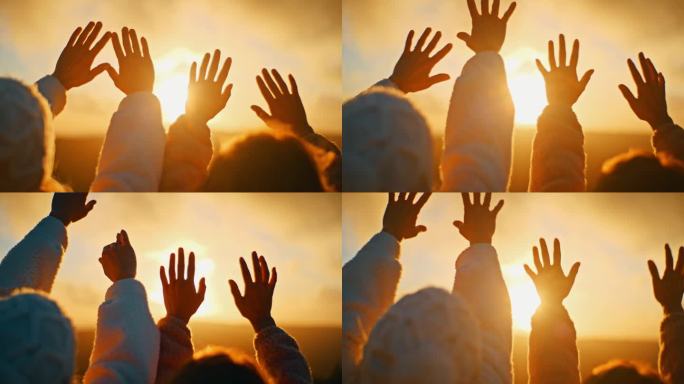 在日出时，年轻的女人举起双手朝向金色的阳光