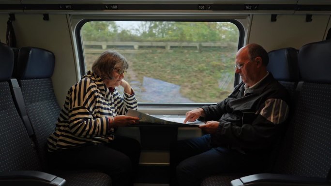 一对老年游客夫妇在火车上阅读城市地图