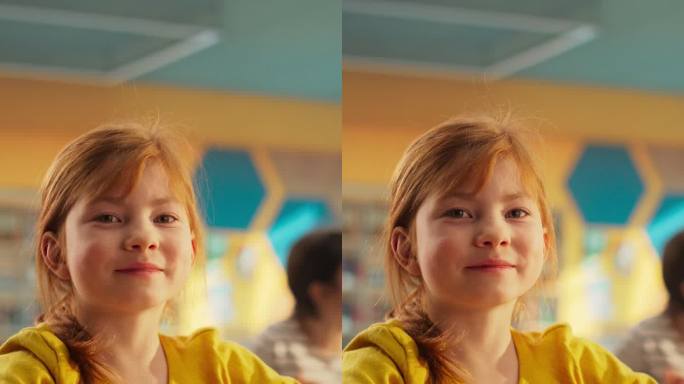 竖屏:一个可爱的红发女孩坐在课桌后面的肖像。小学生微笑着看着镜头。在现代小学接受教育的孩子