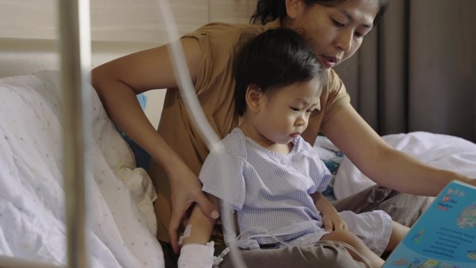 可爱的亚洲孩子感染了病毒，他照顾好自己，和妈妈一起看书，在医院接受抗生素药物和输液盐水，等待康复。婴