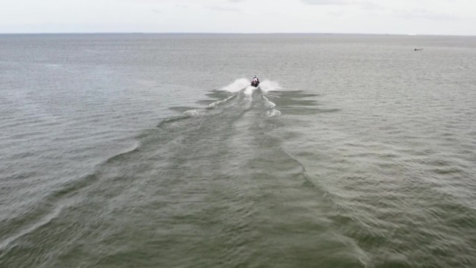 水上摩托艇掠过海面，在它的尾迹上留下泡沫的痕迹