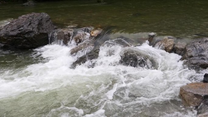 山野河水流过巨石。中国湖北省恩施市鹿源坪清溪。冷水迅速飞溅。岩石上的小瀑布。水背景概念，4k慢动作。