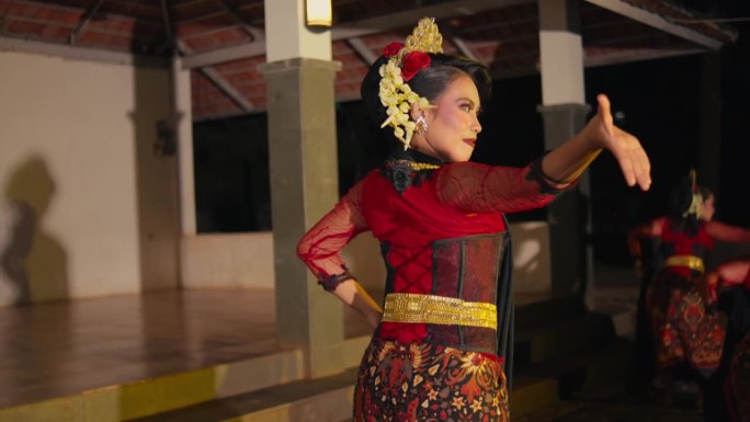 一群舞蹈演员在亭子里表演传统的印尼舞蹈，动作灵活