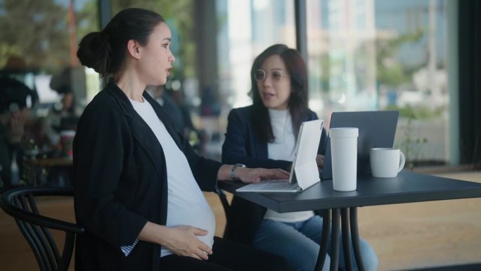 两个怀孕的职业妇女在一个时尚的咖啡店见面，在一个项目会议。