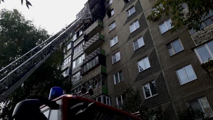 站在防火梯上的消防员正在用水扑灭高层建筑的阳台。消防员在城市里工作