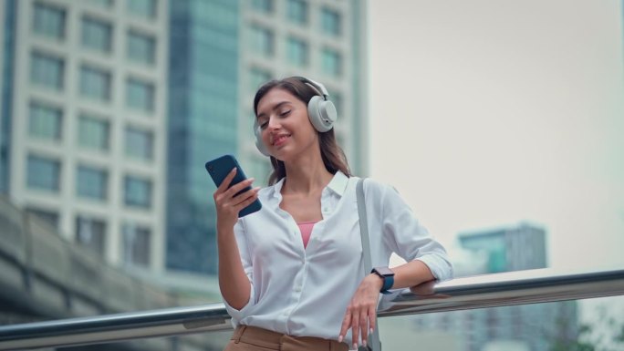 在城市上班的路上玩手机听音乐的女人，心情愉快