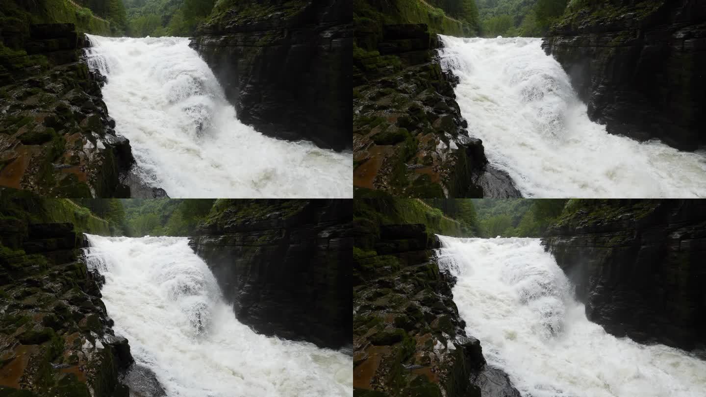 峡谷之间湍急的瀑布河。大雨过后，泥土正在往下移。巨大的棕色浑水在大岩石之间翻滚。4k慢动作镜头b滚拍