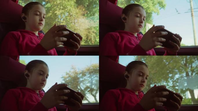 高加索漂亮的小女孩乘坐公共交通工具坐在座位上在车窗边使用手机。在耳朵里使用耳机。带着智能手机在火车里
