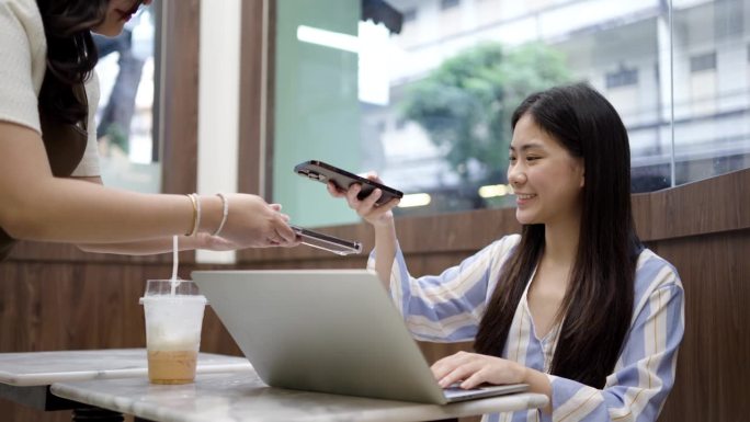 亚洲客户使用智能手机扫描条形码通过银行应用程序与咖啡厅餐厅服务员，无现金二维码技术和汇款概念进行支付