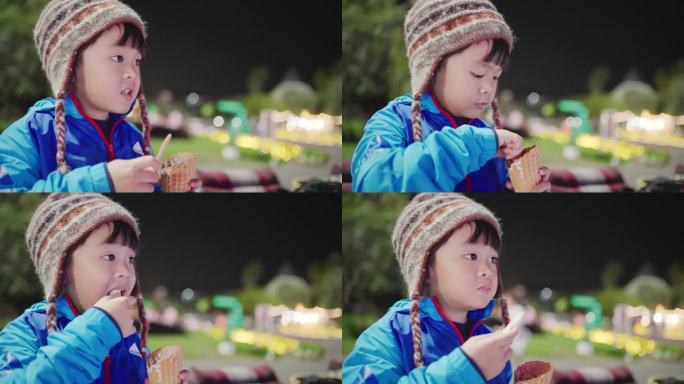 亚洲母亲和儿子晚上坐在公园里享受冰淇淋甜筒。