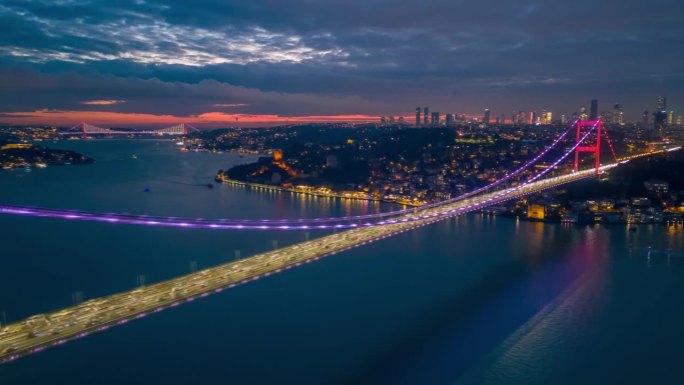 空中超延时魔法:标志性的法提赫苏丹穆罕默德桥和伊斯坦布尔金融区在暮色中闪烁着鲜艳的色彩和动态模糊