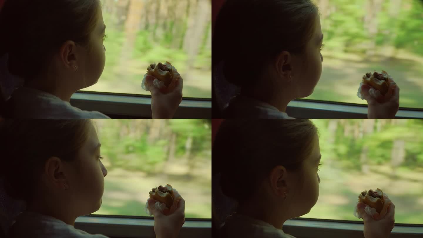 坐火车旅行的小孩在吃三明治。关闭了。孩子若有所思地望着窗外绿色的大自然