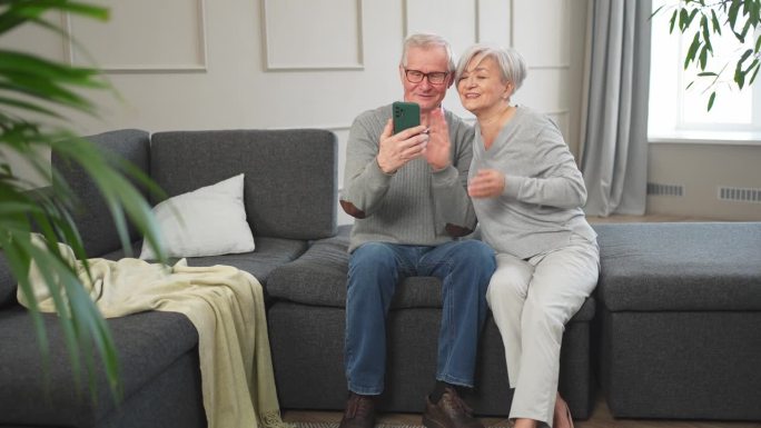 视频电话。快乐的老年夫妇，女人和男人用智能手机进行视频通话。成熟的老奶奶老爷爷在网上说话说话。老一辈