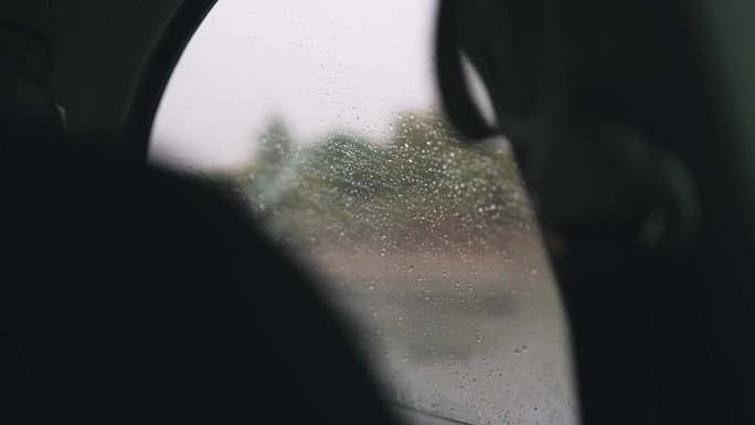 春雨中驾车行驶在湿滑的道路上，透过布满雨滴的车窗望去，在雨中驾车，慢动作的电影镜头