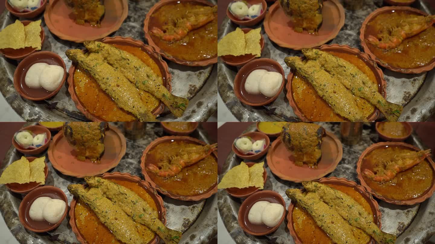 多道菜的电影镜头，如鱼，拉斯gullas, papad，沙沙，对虾，酥油和其他一些菜给予粘土盘和保存