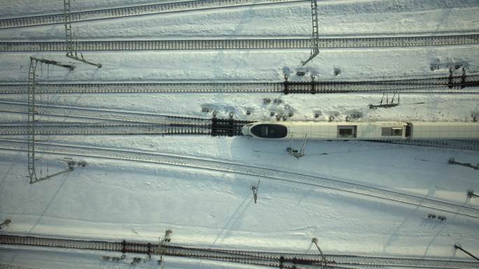航拍冬季雪地高铁火车在铁轨行驶
