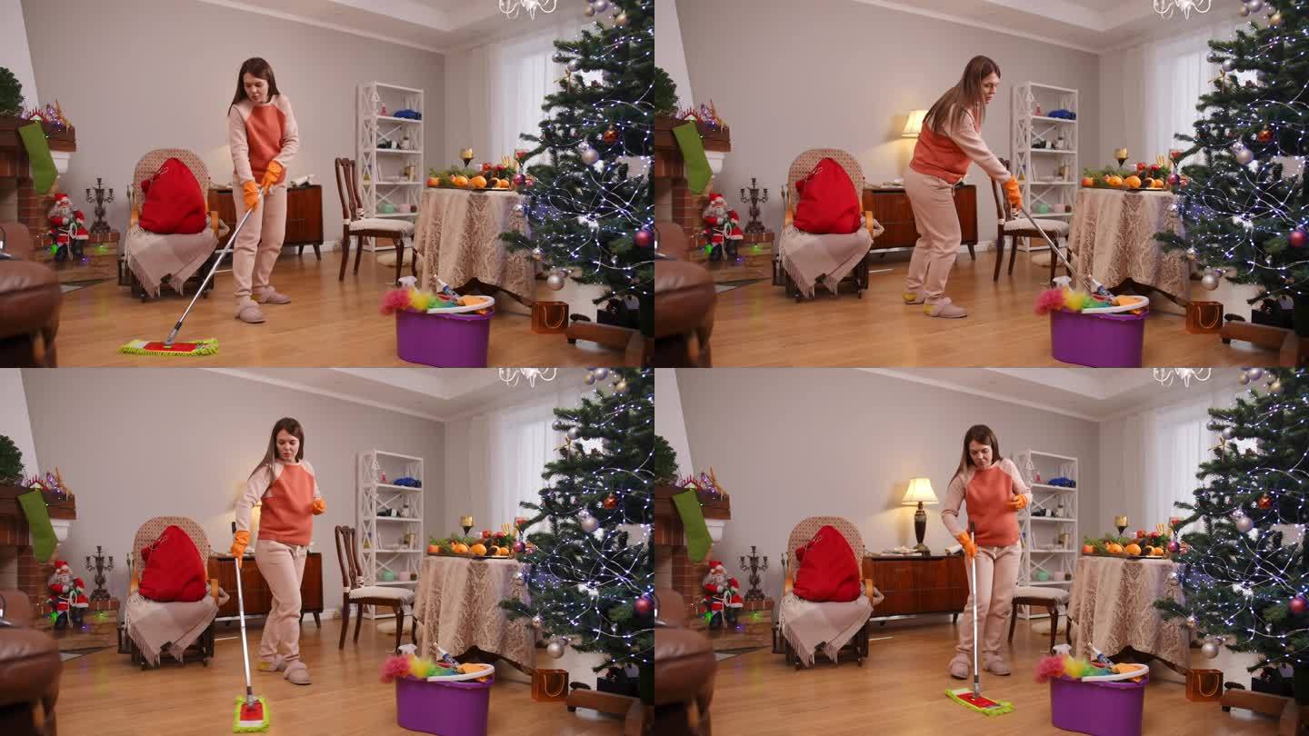 圣诞节前，一位孕妇在客厅的木地板上用拖把擦水。这个女人心情很好，面带微笑。